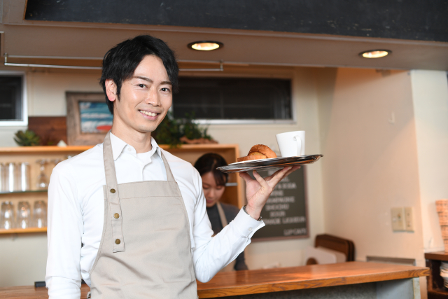 店内で料理を運ぶ飲食店スタッフ