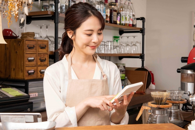 電卓で費用を計算するカフェスタッフ