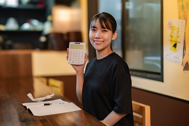 電卓を手に固定費を見直す飲食店スタッフ