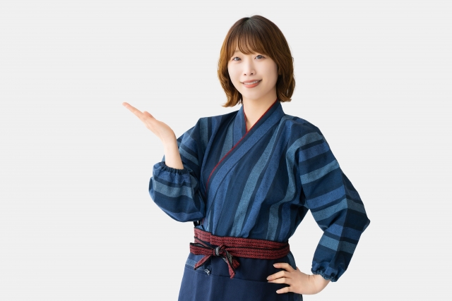 手のひらを向けて案内する和装の女性