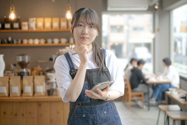 スマートフォンを持ちマーケティングを考える飲食店スタッフ