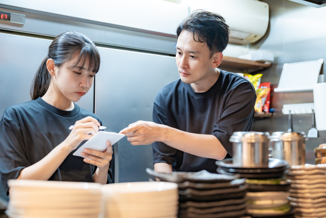 厨房で新人スタッフへ指導する店長